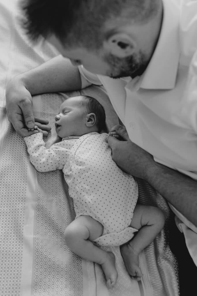 Black and white image for newborn baby boy and his dad holding his hands. Newborn photo shoot in London. Ewa Jones Photography