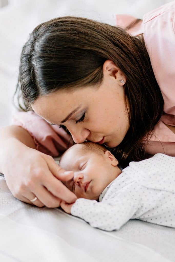 Mum is kissing her baby boy on his head. Baby boy is sleeping. Natural lifestyle photosession in London. Ewa Jones Photography