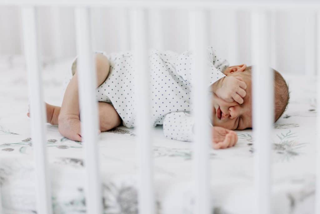 Newborn baby is laying and sleeping in his baby cot. Hampshire newborn photographer. Ewa Jones Photography
