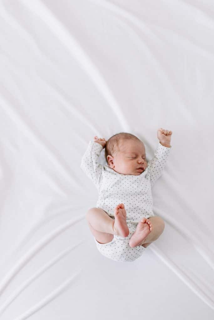 Newborn baby boy is stretching on the bed. Basingstoke photographer. Ewa Jones Photography