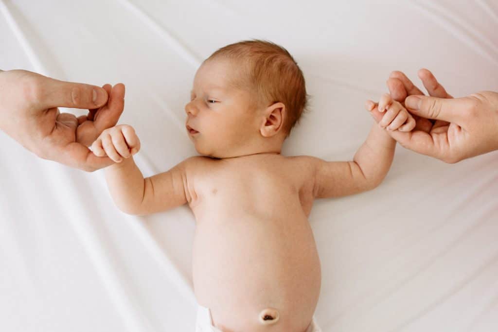 Mum and dad are holding newborn baby boy hands. Natural lifestyle newborn photo shoot in London. Ewa Jones Photography