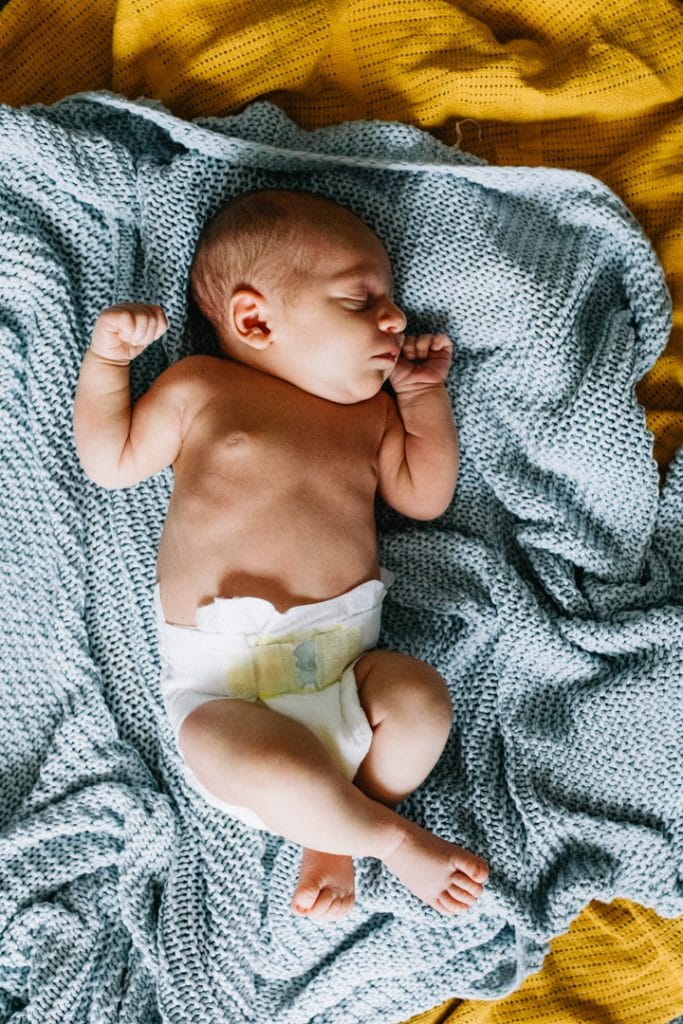 Little newborn baby boy is laying on blankets and sleeping. Newborn photoshoot in Basingstoke, Hampshire. Ewa Jones Photography