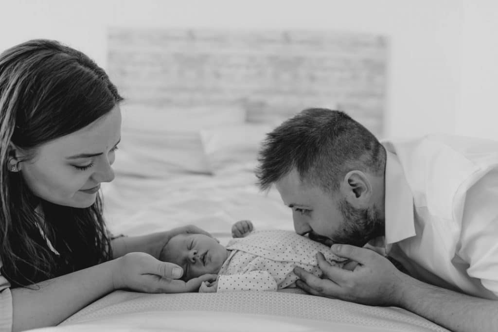 Parents are looking at the newborn baby and dad is kissing his boy. Newborn photo session in London. Ewa Jones Photography