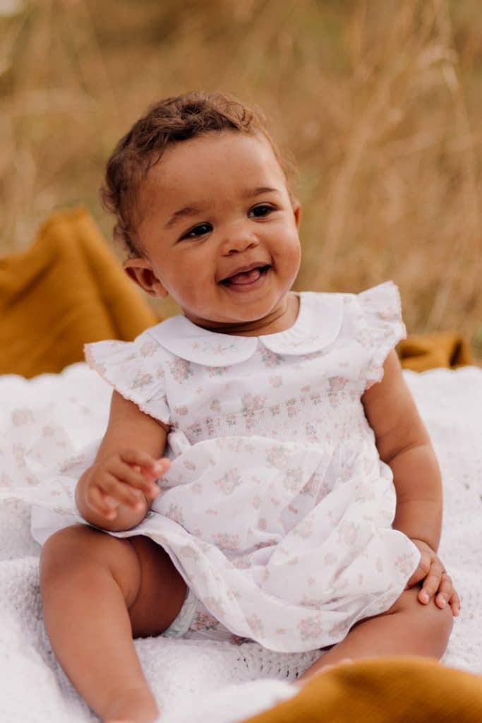 little girl is sitting on the blanket and smiling. candid natural lifestyle photo session. family photographer in Hampshire. Ewa Jones Photography