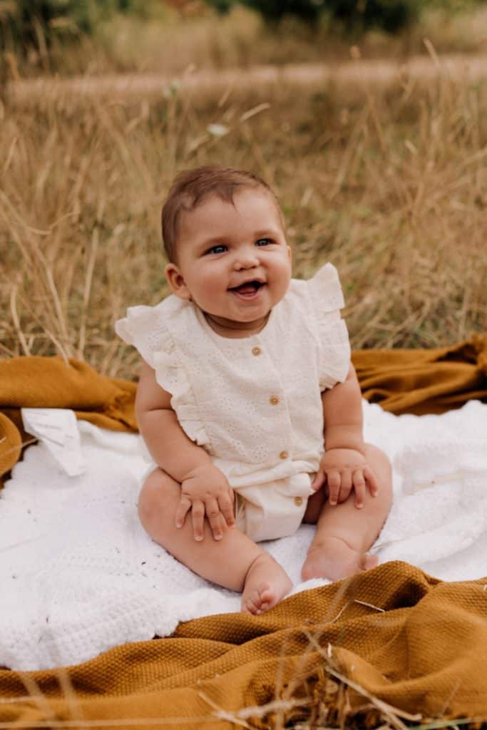 little baby girl is sitting on the blanket and smiling. family photo session. Hampshire photographer. Ewa Jones Photographer