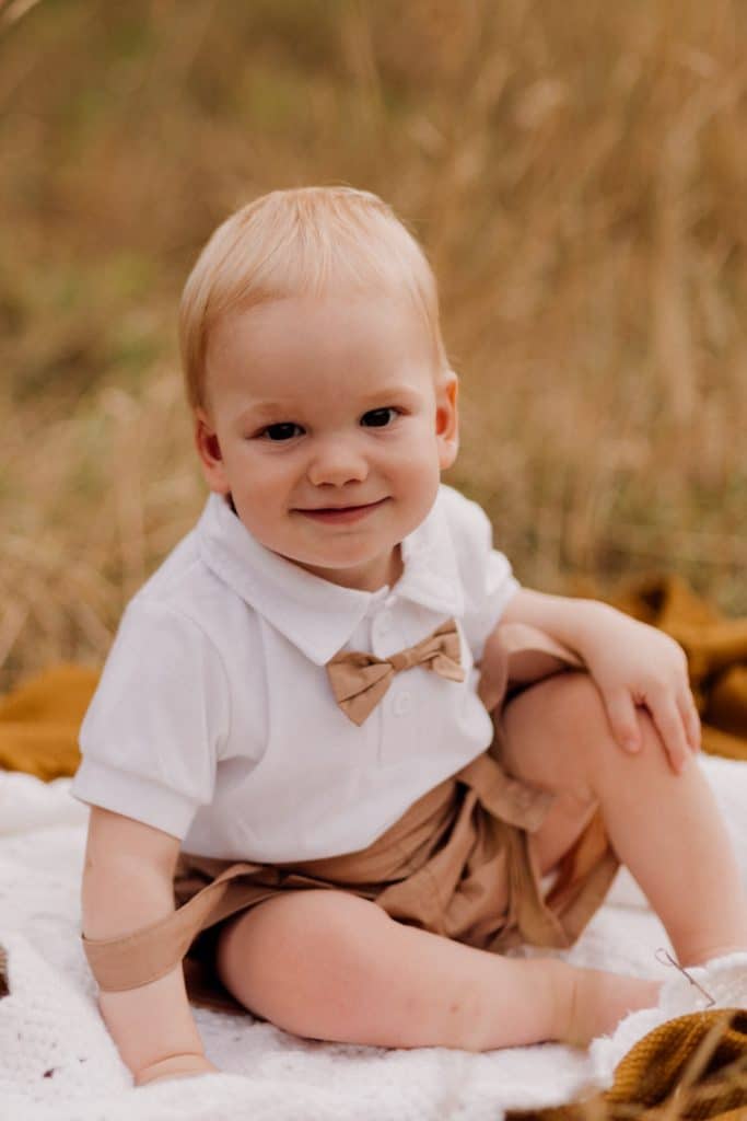little boy is sitting on the blanket and smiling. Natural lifestyle family photographer. Hampshire photography. Ewa Jones Photography