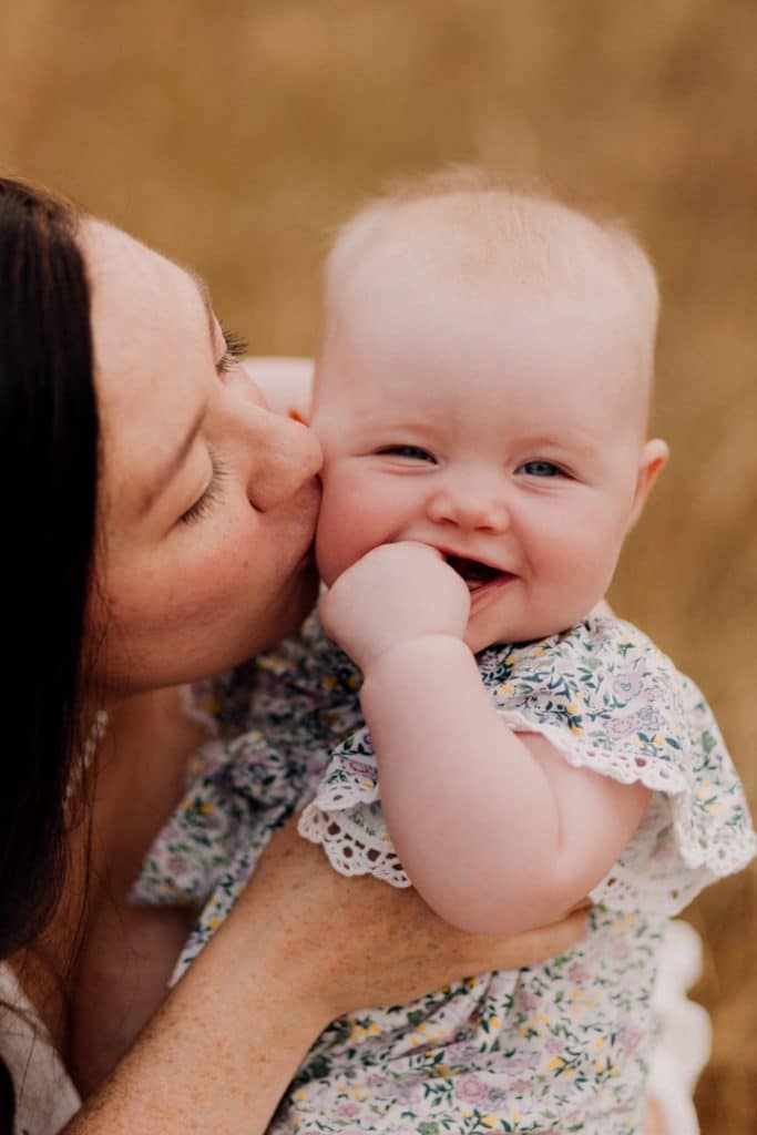 mum is kissing her baby girl in her cheek. summer photo session in the wild flowers. Basingstoke photographer. Ewa Jones Photography. love, connection.