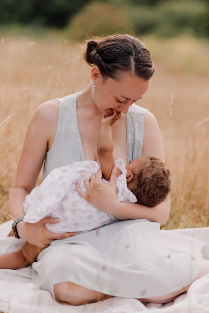 mum is sitting on the blanket and breastfeeding her baby girl. Summer photo session. breastfeeding week. group breastfeeding photo session. Hampshire photographer. Ewa Jones Photography