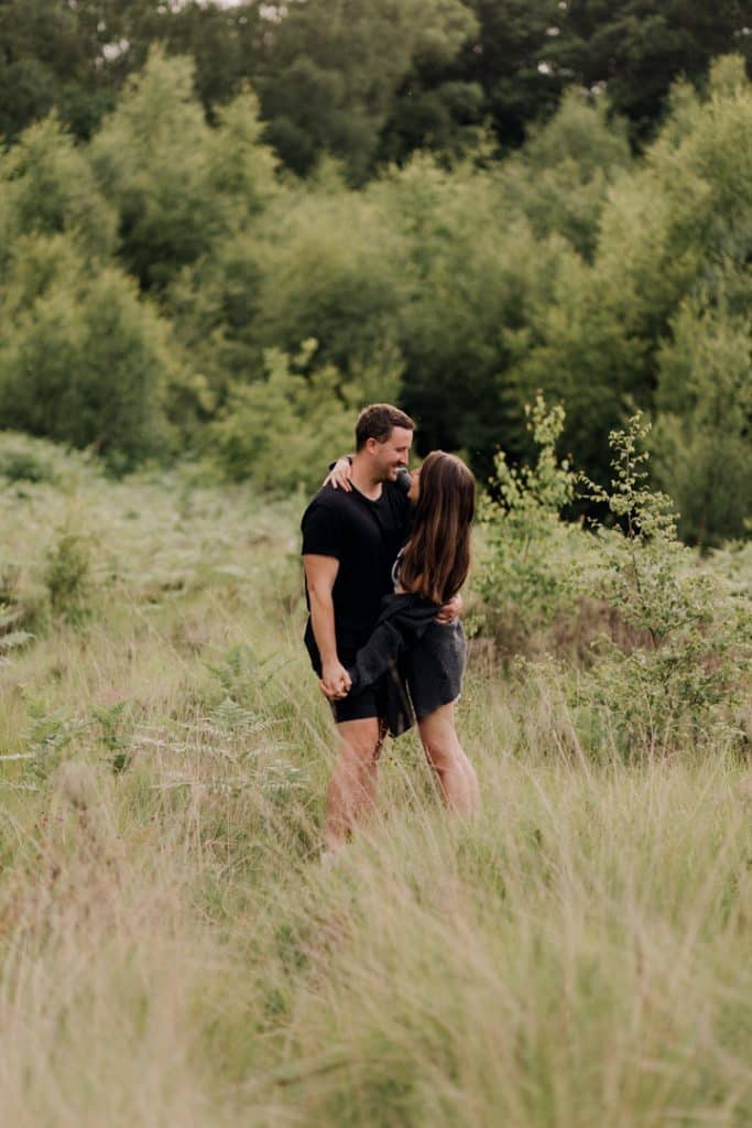 couple is looking at each other and sanding in the wild field. engagement photographer in Hampshire. Ewa Jones Photography