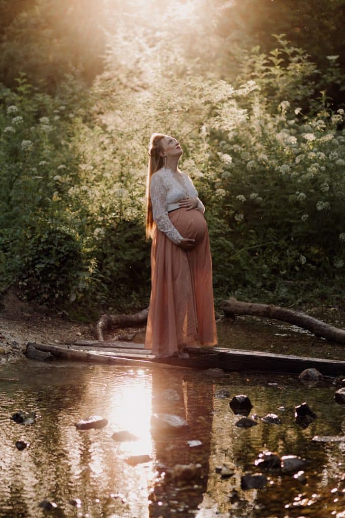 Maternity photo session - Grace and Chris-17 pregnant mum is standing next to the stream and looking up. Lovely maternity dress. maternity photo session in Hampshire. Hampshire photographer. Ewa Jones Photography