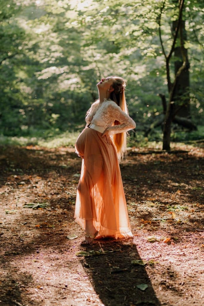 Maternity photo session - Grace and Chris-6 Mum is standing in the forest and looking up to the sky. What to wear for your maternity photo session. Maternity photo session in the woods. Hampshire photographer. Ewa Jones Photography
