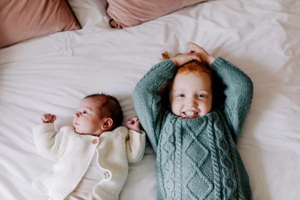 two sisters are laying on the bed. Newborn lifestyle photo session. Newborn photographer. Ewa Jones Photography