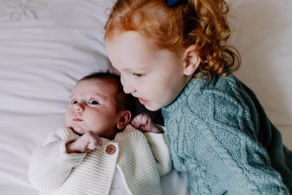 big sister is cuddling her newborn sister. Newborn photographer in Berkshire. Ewa Jones Photography