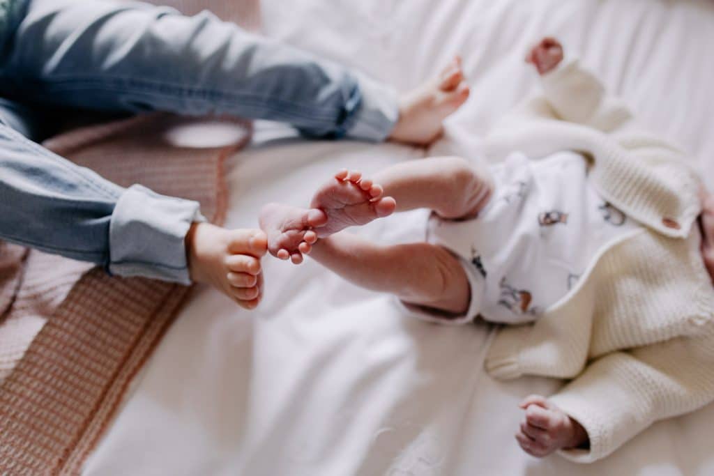 two sisters are measuring their feet. Newborn and toddler photo shoot ideas. Newborn photo session. Hampshire photographer. Ewa Jones Photography