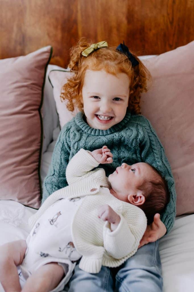 big sister is holding her newborn baby sister. lovely natural lifestyle newborn photo session. Hampshire newborn photography. Ewa Jones Photography
