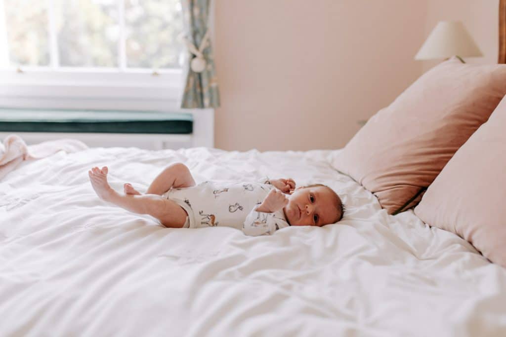 newborn baby girl is laying on bed and looking at the camera. Newborn photo session in Berkshire. Hampshire photographer. Ewa Jones Photography