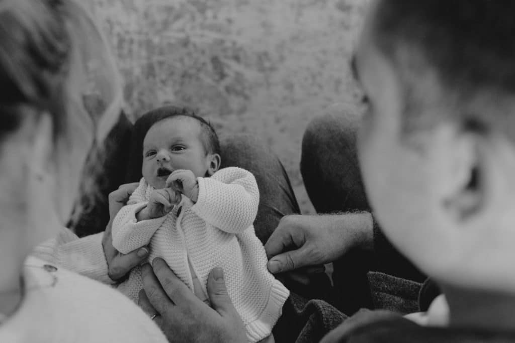 mum and dad are looking down at their newborn baby girl. Lifestyle photo shoot at home. Newborn photography in Hampshire. Ewa Jones Photography