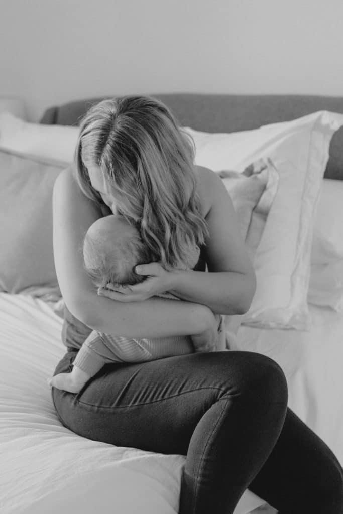 black and white image of mum kissing and cuddling her newrborn baby. Newborn baby lifestlye photo session. Ewa Jones Photography