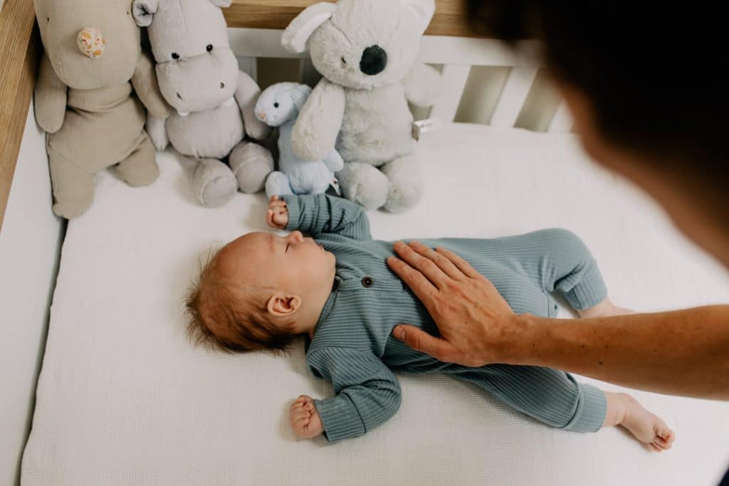 Baby boy is sleeping and dad has his hand on his tummy. Newborn photo session in Hampshire. Ewa Jones Photography