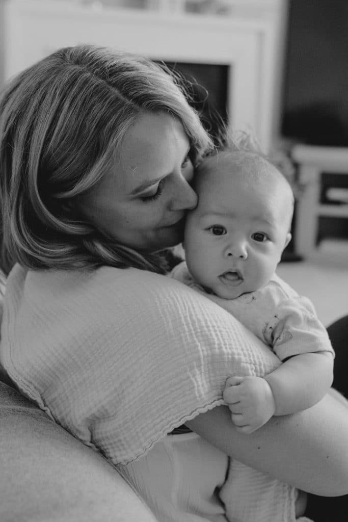 mum is cuddling her baby boy close and the baby boy is looking at the camera. lovely baby photo shoot at home. Hampshire baby photographer. Ewa Jones Photography