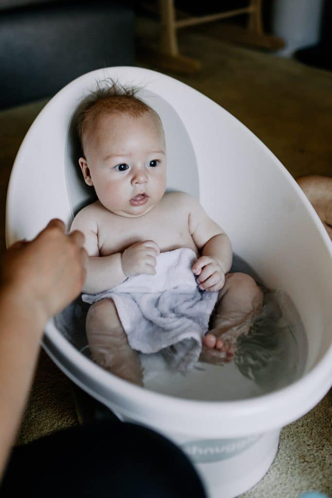 baby boy is having a bath. natural lifestlye family photo session in Hampshire. Hampshire newborn photographer. Ewa Jones Photography