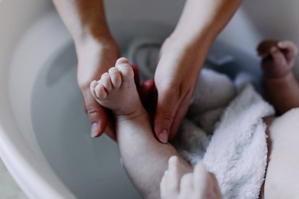 mum is washing baby boy feet in the bath. lifestlye baby photography in Hampshire. Hampshire newborn photographer. Ewa Jones Photography