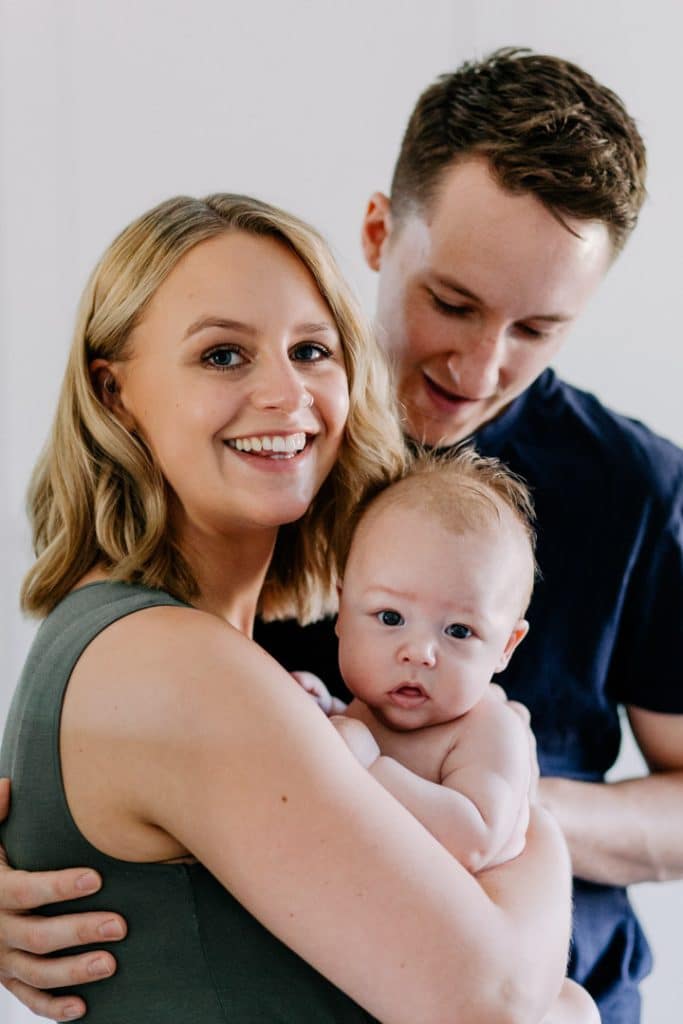 family of three is cuddling. mum is holding her baby boy and dad is cuddling them. newborn photo shoot in Hampshire. Ewa Jones Photography