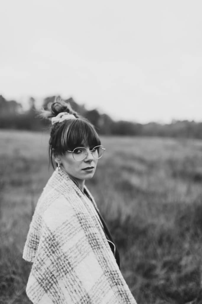 Black and white image of female standing and looking at the camera. she has nice scarf over her shoulders. Female photo session in Hampshire. Hampshire photographer. Ewa Jones Photography