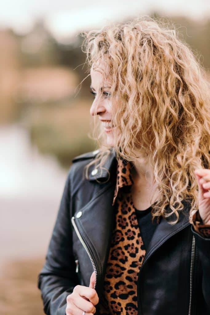 woman is looking away and smiling. She is wearing black leather jacket. female photo session. Empowering female session. Hamphire photographer. Ewa Jones Photography