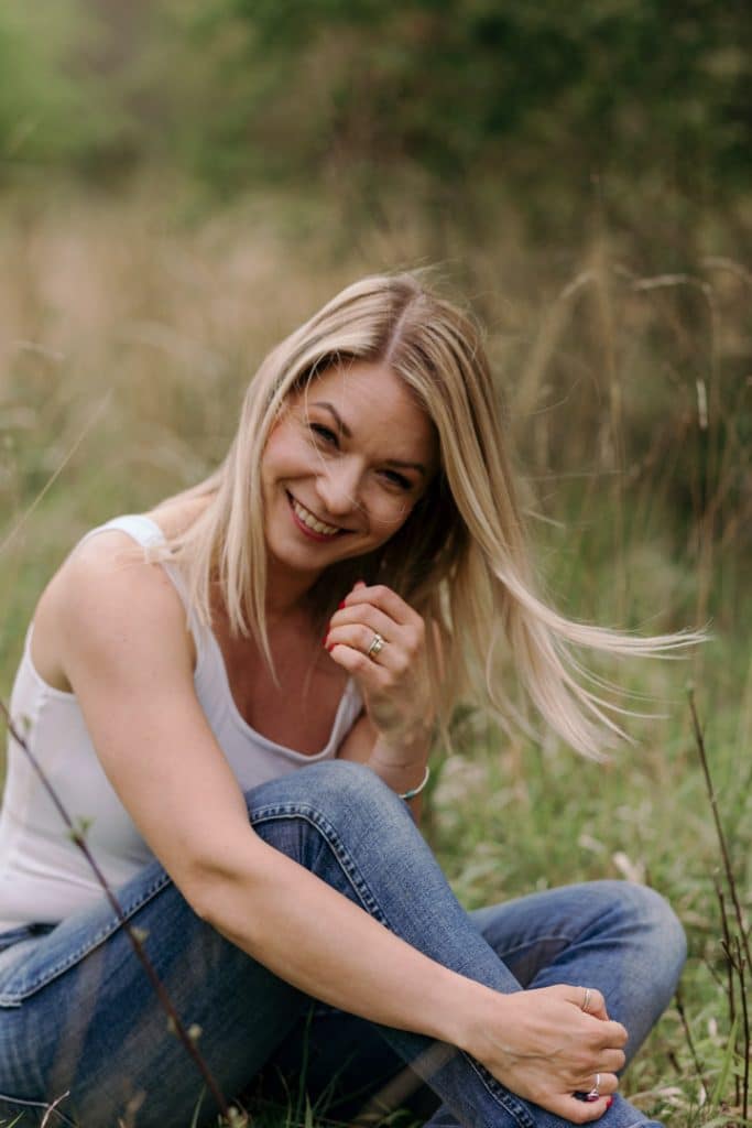 female is sitting on the grass and smiling to the camera. natural lifestyle female empowering photo sessions. Hampshire photographer. Ewa Jones Photography empowering female photo sessions