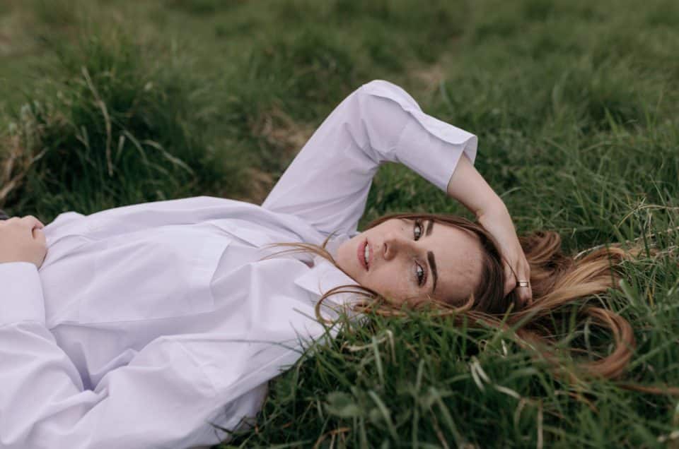 female poses for female photo session. lovely image of female laying on the grass and looking at the camera. women photo session in Hampshire. Hampshire photographer. Ewa Jones Photography. empowering female photo sessions