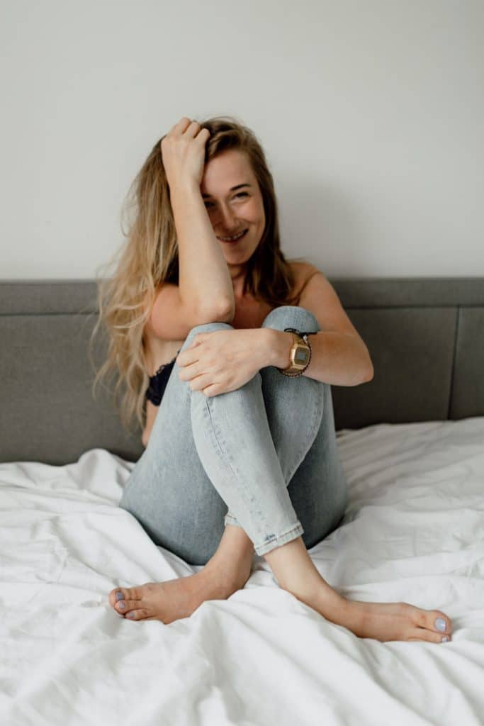 woman is sitting on the bed and laughing. Female intimate boudoir session in Basingstoke hamsphire. Hampshire photographer. Basingstoke female photographer.Ewa Jones Photography