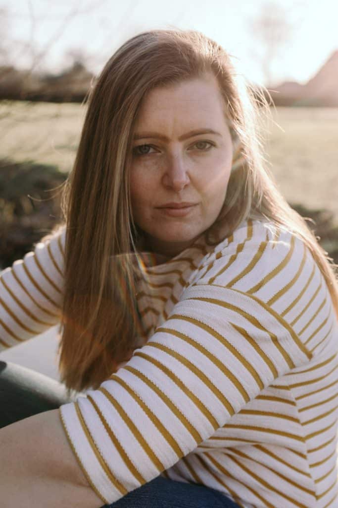 Lovely woman is sitting down and looking at the camera. She is wearing white top with stripes. Female photo sessions in Basingstoke Hamphire. Hampshire photographer. Ewa Jones Photography
