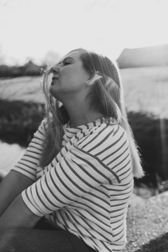 black and white image of a female sitting and moving her hair. Natural unposed female photo session in Basingstoke Hampshire. Basingstoke photographer. Ewa Jones Photography