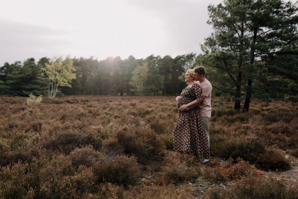 Expecting parents are standing in the field and cuddling. Lovely natural matenrity photo session. Hampshire family photographer. Ewa Jones Photography