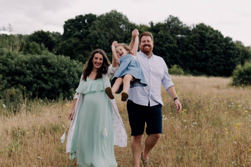 Mum and dad are doing a swing with their little toddler girl. Maternity photo shoot in Basingstoke. Ewa Jones Photography
