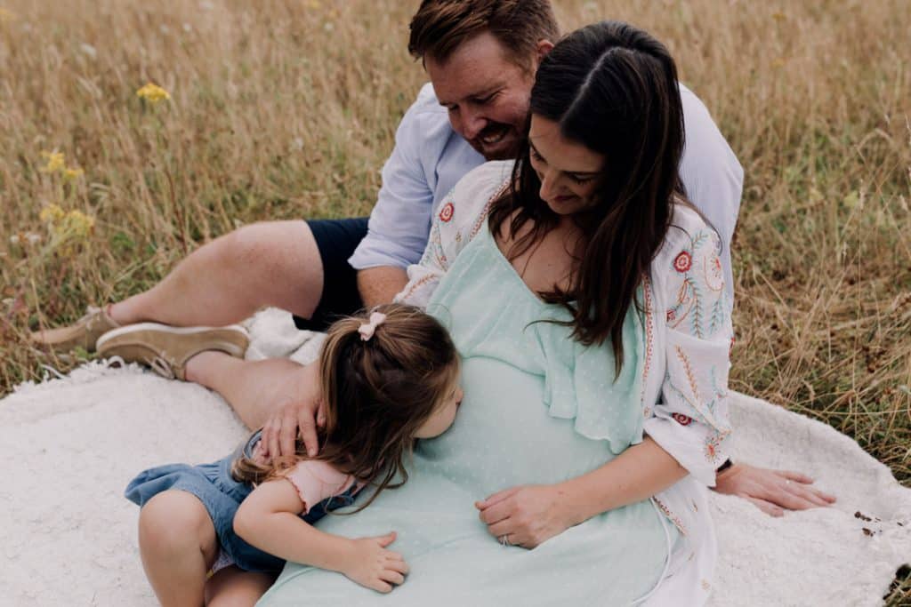Toddler girl is kissing her mummy's baby bump. Maternity family photo session in Basingstoke Hampshire. Ewa Jones Photography