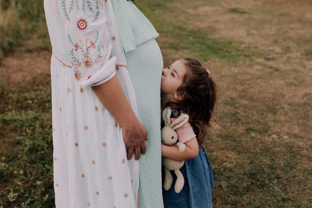 little girl is kissing mummys tummy. Matenrity photo shoot with a toddler. Maternity photographer in Hampshire. Ewa Jones Photography