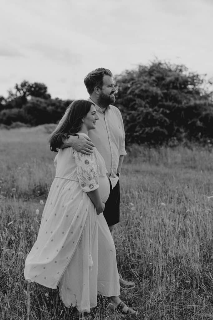 Mum and dad are hugging and looking away. Hampshire maternity photographer. Ewa Jones Photography
