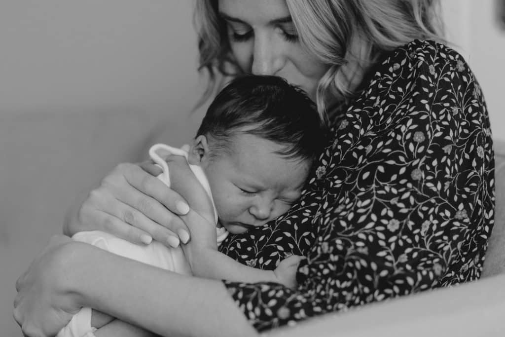Mum is kissing her newborn baby. Black and white image. Newborn photo shoot in Basingstoke Hampshire. Ewa Jones Photography
