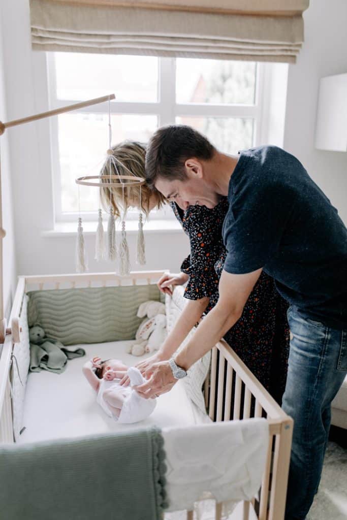 mum and dad are standing next to the baby bed and looking dwon on baby. Newborn baby posing ideas. Newborn photography. Ewa Jones Photography