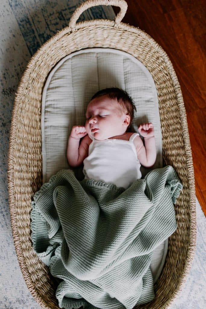 newborn baby girl is laying in her moses basket and sleeping. lovely lifestlye photo. Newborn photo shoot in Basingstoke Hampshire. Ewa Jones Photography
