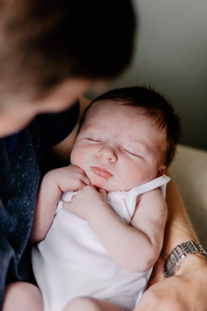 Dad is holding his newborn baby girl close and looking down at her. Newborn photo shoot in Basingstoke Hampshire. Ewa Jones Photography