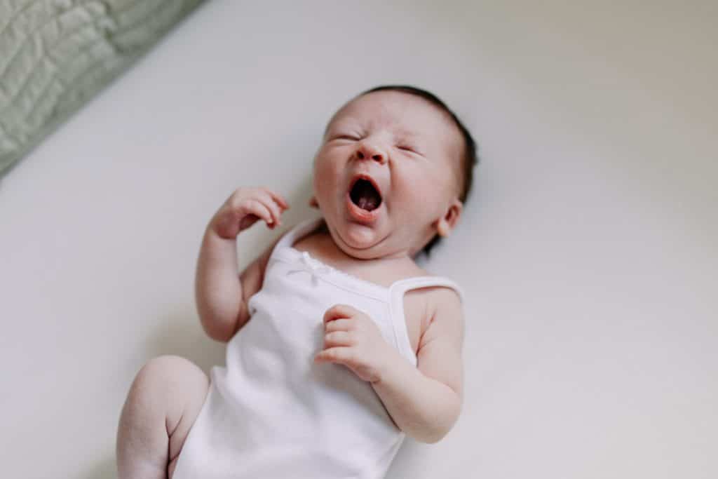 Baby is laying on bed and yawning. Lovely newborn photo shoot at home. Newborn photography in Basingstoke. Ewa Jones photography