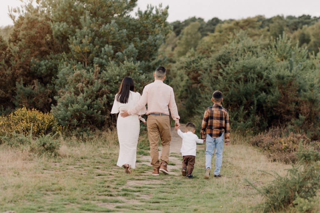 family of four is walking in the field. Lovely family photo session in Surrey. Ewa Jones Photography. Hampshire photographer