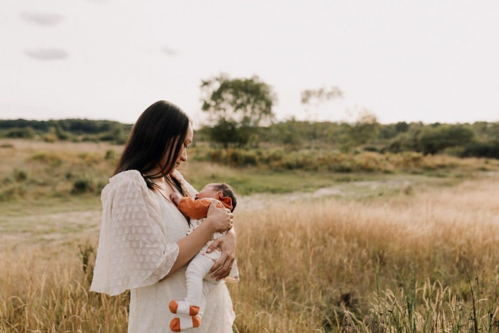 Mum is holding her baby girl close in her hands. Baby girl is sleeping. Lovely late summer family photo session in Septemer. Hampshire family photographer. Ewa Jones Photography