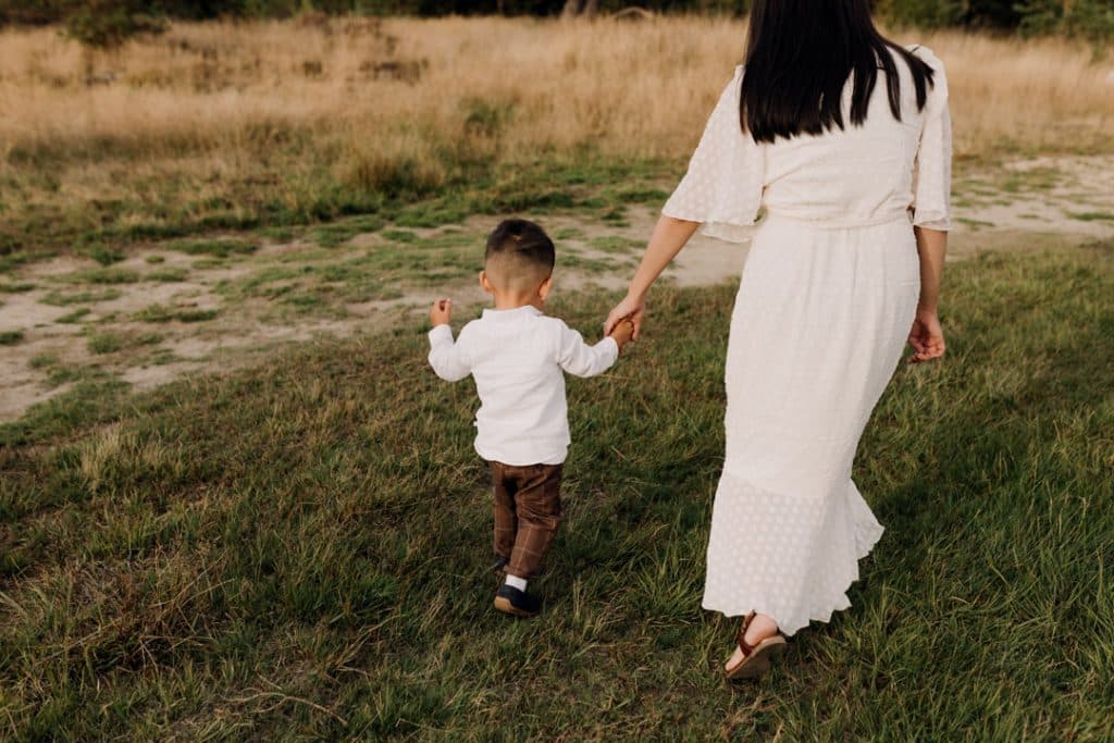 Mum is holding her little boy hand and walking away. Family photo session in Hampshire. Ewa Jones Photography