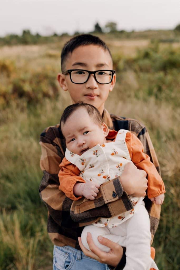 Older brother is holiding his baby sister. Lovely late summer family photo session in September. family photographer in Surrey. Ewa Jones Photography