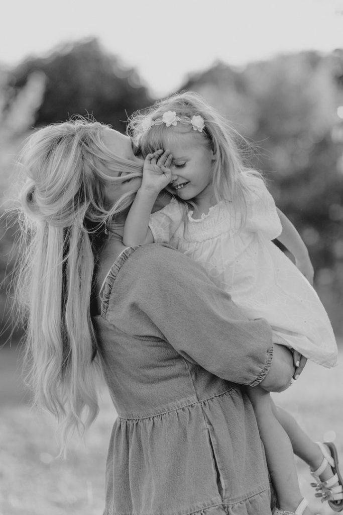 mum is cuddling and kissing her little girl. black and white family photography. Hampshire family photographer. Ewa Jones Photography