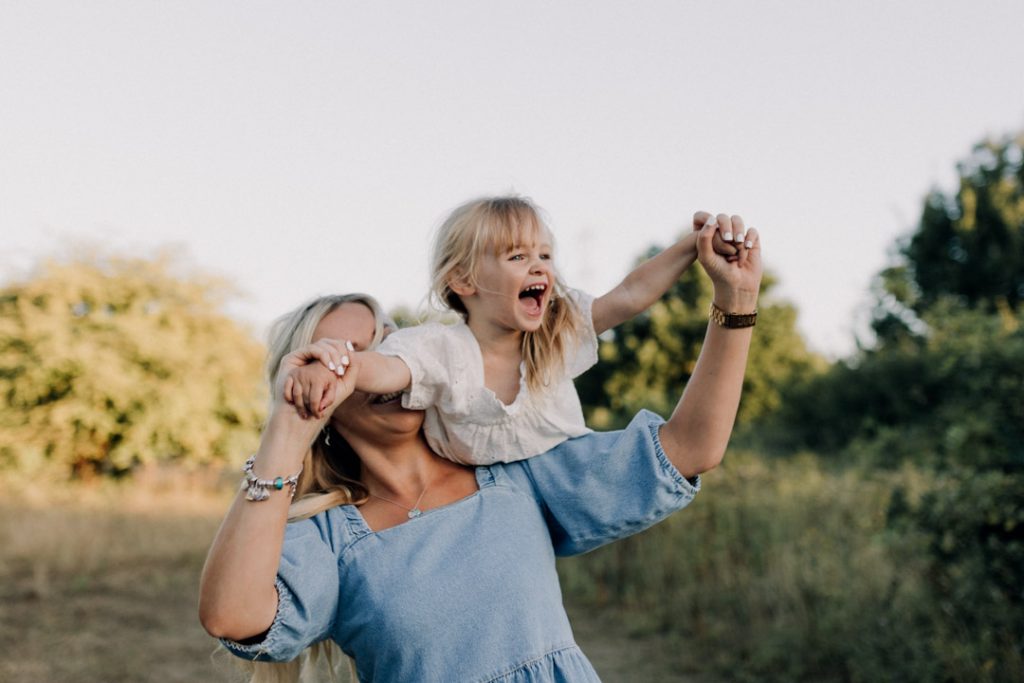 mum is holding her little girl and she is on mummys shoulder laughing. Laugh giggles and happiness. Hampshire family photographer. Ewa Jones Photography